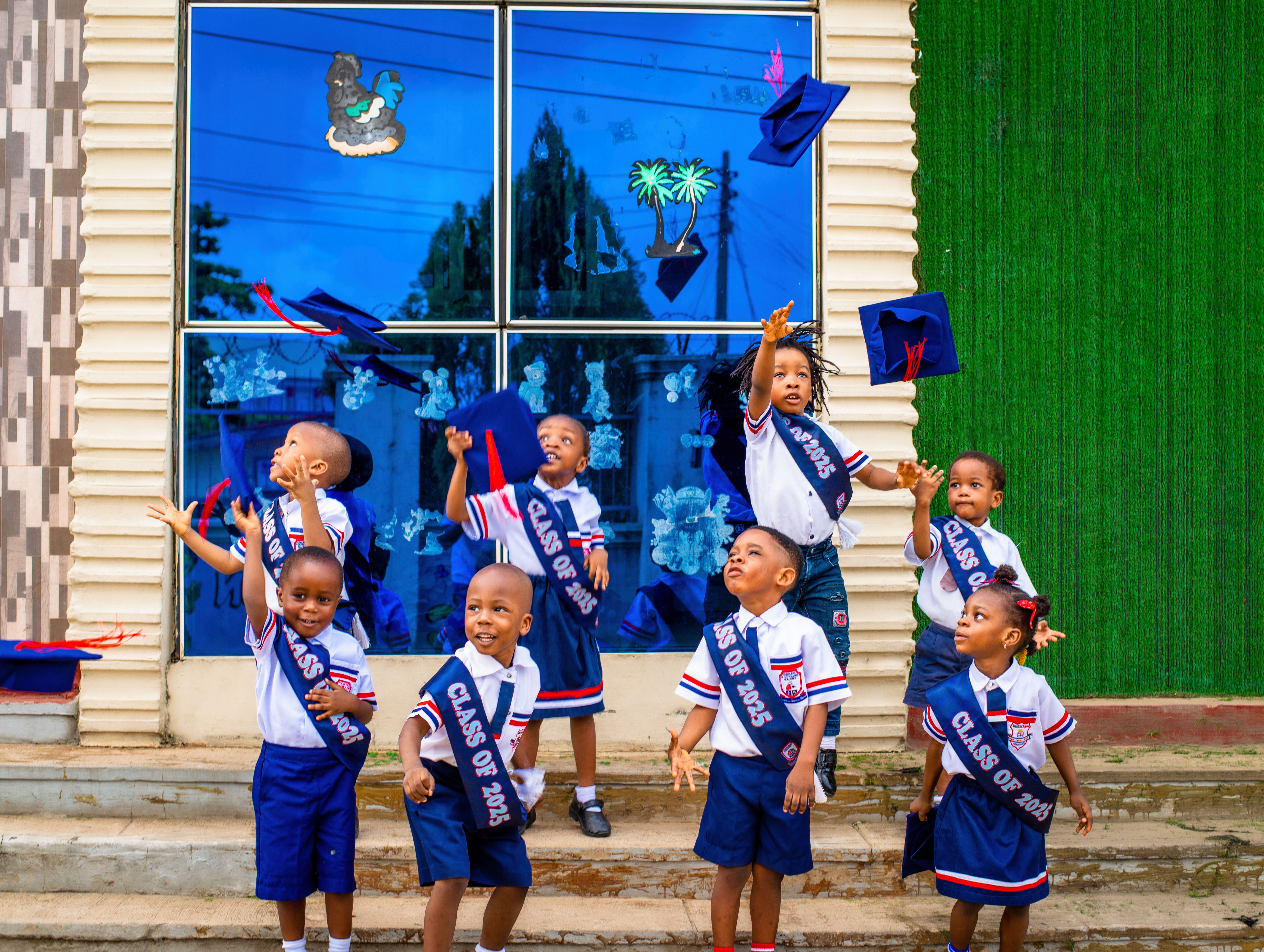 Graduating children throwing caps in the air